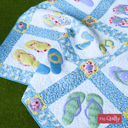 The Flip Flop Quilt Downloadable PDF Quilt Pattern features playful appliqué flip-flops in vibrant patterns, finished with a charming blue and white floral border—perfect for adding color to any space.