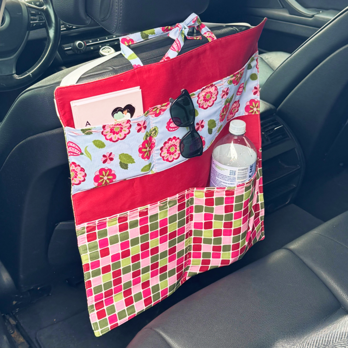 The Car Organizer Downloadable PDF Quilt Pattern lets you create a seat-back organizer with multiple patterned, quilted pockets for storing items like water bottles, sunglasses, and cards.