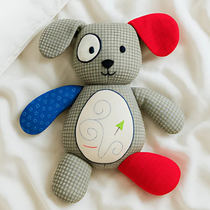 Patches the Puppy Downloadable PDF Quilt Pattern features a patchwork puppy with mismatched blue and red ears and legs, a gray checkered body, and an embroidered spiral belly—perfect inspiration for beginner quilters.