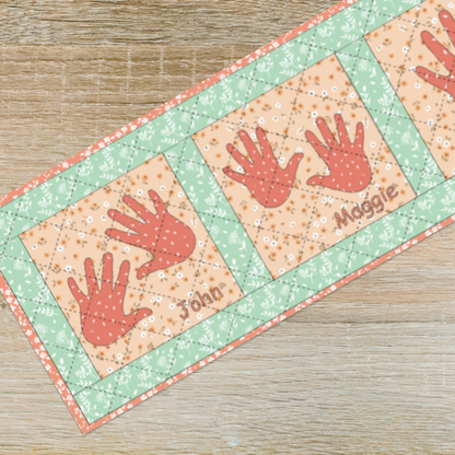 The Hand in Hand Table Runner Downloadable PDF is a charming quilting project; personalize it with names like "John" and "Maggie" to create a treasured heirloom for your wooden table.