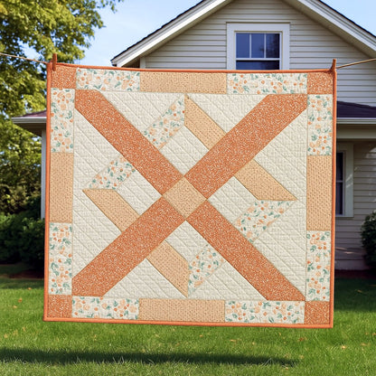 The X Frame Quilt Downloadable PDF Quilt Pattern features an orange and cream geometric design, shown here hanging on a clothesline in front of a white-sided house with a green lawn.